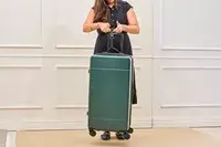 A person weighs the Calpak Hue Trunk Luggage