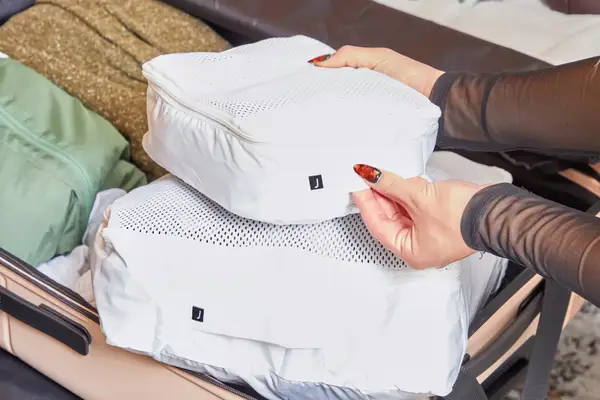 Hands placing packing cubes inside the July Checked Plus Large Luggage