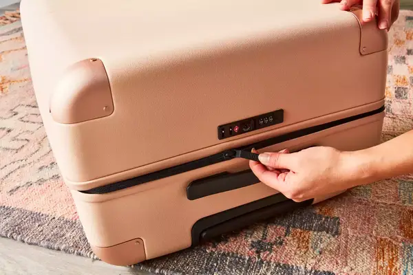 Hand unzipping the July Checked Plus Large Luggage