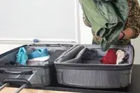 Person packing a green jacket into the Samsonite Winfield 2 Hardside Luggage with Spinner Wheels