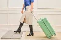 A person wheels the Positano Expandable 27-inch Spinner across a rug