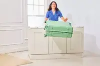 A person throws the Positano Expandable 27-inch Spinner from a table