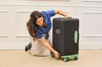 A person places a cover on the Positano Expandable 27-inch Spinner