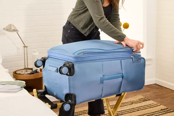 A person zips the front pocket on the Travelpro VersaPack+ Large Check-In