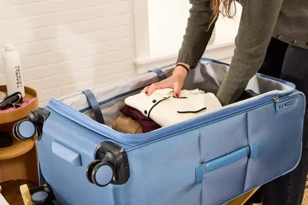 A person places clothing into the Travelpro VersaPack+ Large Check-In