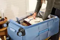 A person places clothing into the Travelpro VersaPack+ Large Check-In