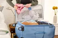 A person places clothing into the Travelpro VersaPack+ Large Check-In pocket