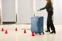A person wheels the Travelpro VersaPack+ Large Check-In over a floor