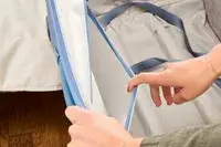 A person opens a pocket on the side of the Travelpro VersaPack+ Large Check-In