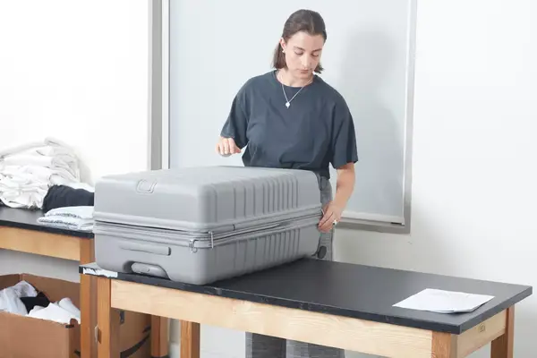 Person zipping the Beis 29-Inch Large Check-in Roller on a table