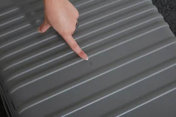 Hand pointing at a small scuff on the Béis The 29-inch Large Check-in Roller