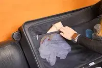 Hand placing an item in a mesh pocket inside the Away The Trunk