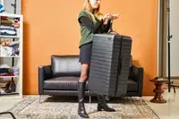 Person weighing the Away The Trunk with a luggage scale