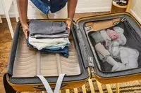 A person places clothing inside the Samsonite Proxis Medium Spinner