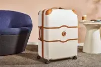 Delsey Paris Chatelet Air 2.0 28 Inch Large Checked Spinner on a carpet next to furniture