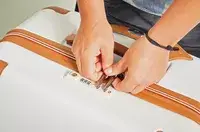 A person locking the Delsey Paris Chatelet Air 2.0 28 Inch Large Checked Spinner