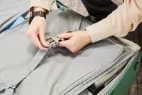 Hands clipping a strap inside the Samsonite Elevation Plus Large Softside Spinner