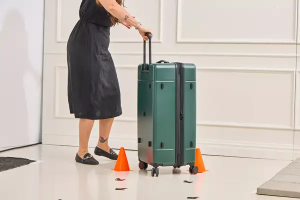 A person rolling the Calpak Hue Trunk Luggage through an obstacle course