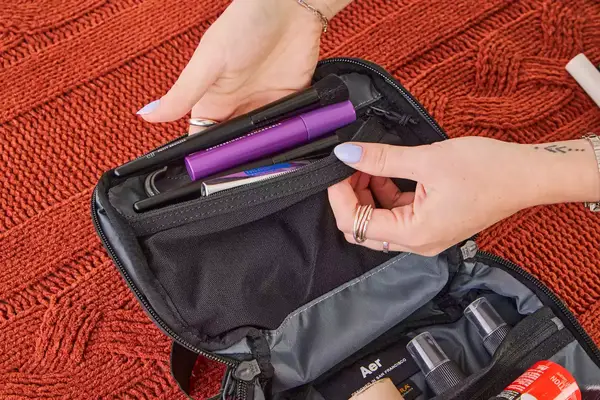 A person places travel items into the Aer Travel Kit 2