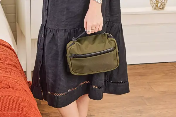 A person holds the Aer Travel Kit 2 by the top handle