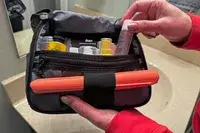 A person places travel items into the Aer Travel Kit 2