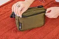 A person zips the front pocket of the Aer Travel Kit 2 closed