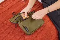 A person places makeup into the Aer Travel Kit 2