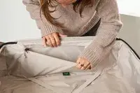 A person holds open a pocket on the Antler Soft Stripe Lightest Large Luggage