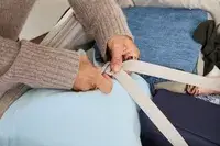 A person secures the straps on the Antler Soft Stripe Lightest Large Luggage