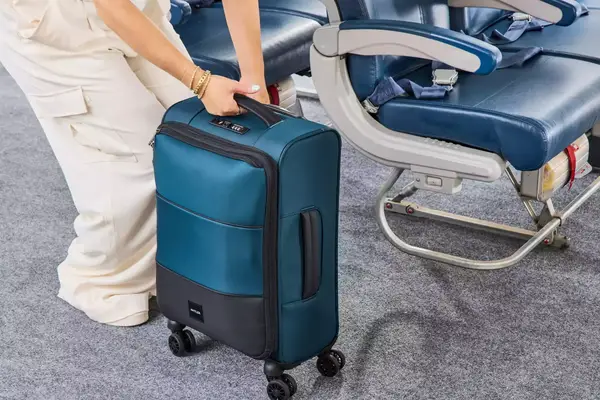 A person prepares to lift the Antler Soft Stripe Carry-On by the top handle