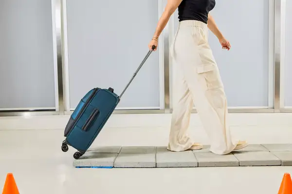 A person rolls the Antler Soft Stripe Carry-On over stone pavers