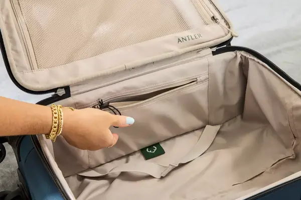A person unzips the side pocket on the Antler Soft Stripe Carry-On