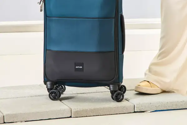 A person wheels the Antler Soft Stripe Carry-On over stone pavers