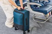 A person prepares to lift the Antler Soft Stripe Carry-On by the top handle