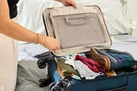 A person packs the Antler Soft Stripe Carry-On with clothing