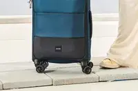 A person wheels the Antler Soft Stripe Carry-On over stone pavers