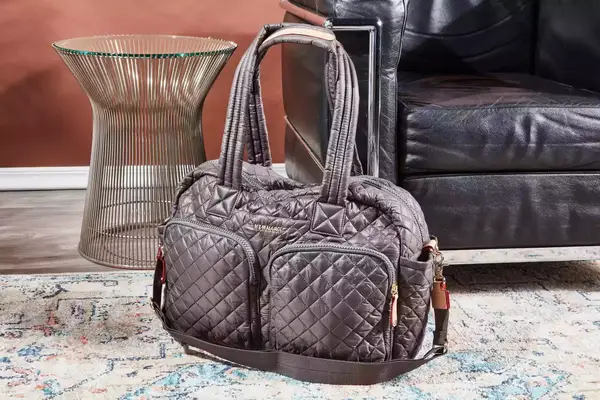 MZ Wallace Nik Duffel displayed in front of a leather sofa