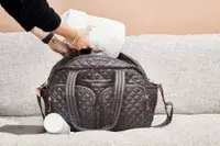 Hands packing clothing into the MZ Wallace Nik Duffel