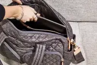 Hand putting a laptop into the MZ Wallace Nik Duffel
