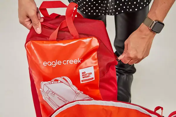 A person places the Samsonite Uplift Hardside Carry-on into an overhead compartment