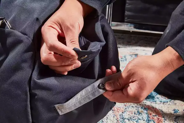 Hands unsnapping part of the Bellroy Classic Weekender 45L