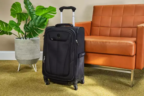 Travelpro Maxlite 5 Softside Expandable Carry-on Spinner standing on a carpet in front of a chair