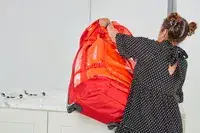 A person rolls the Samsonite Uplift Hardside Carry-on over a rug