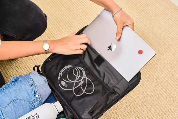 A person placing their laptop into the sleeve of the Calpak Luka Soft-sided Mini Carry-on Luggage