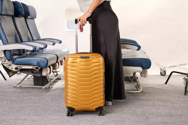 A person wheels the Samsonite Proxis Global Carry-On Spinner down an airplane aisle