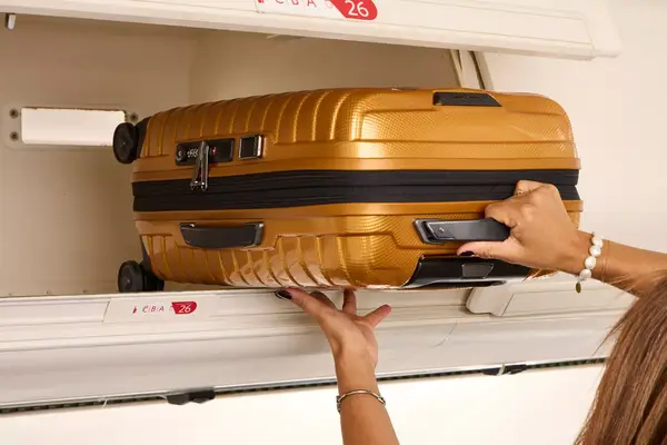 A person lifting the Samsonite Proxis Global Carry-On Spinner into the overhead bin