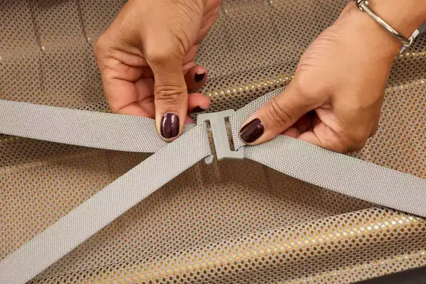 A person secures a strap on the Samsonite Proxis Global Carry-On Spinner