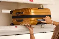 A person lifting the Samsonite Proxis Global Carry-On Spinner into the overhead bin