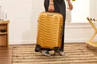 A person holding the Samsonite Proxis Global Carry-On Spinner by its handle