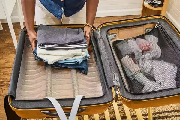 A person places clothing inside the Samsonite Proxis Medium Spinner